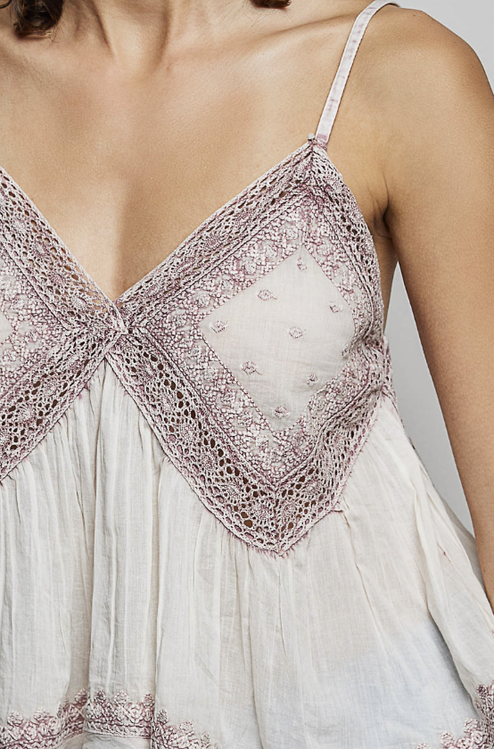 Close-up of a white dress with lace detailing on a neutral background