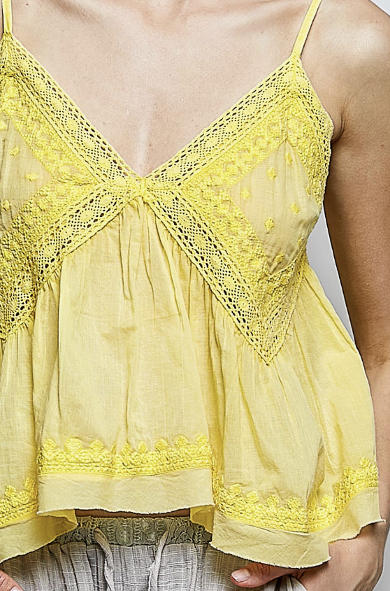Yellow lace-trimmed top worn by a person, with a neutral background