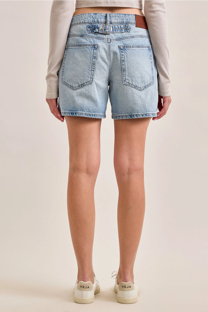 Back of woman wearing denim shorts on plain background