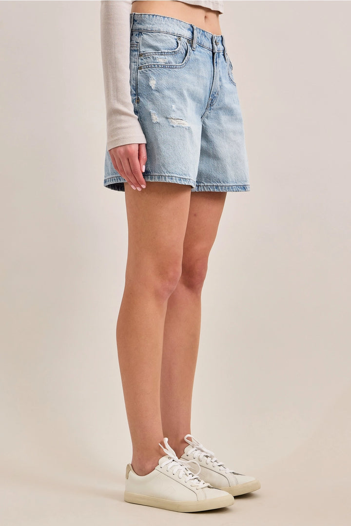 Woman wearing denim shorts and tennis shoes on plain background