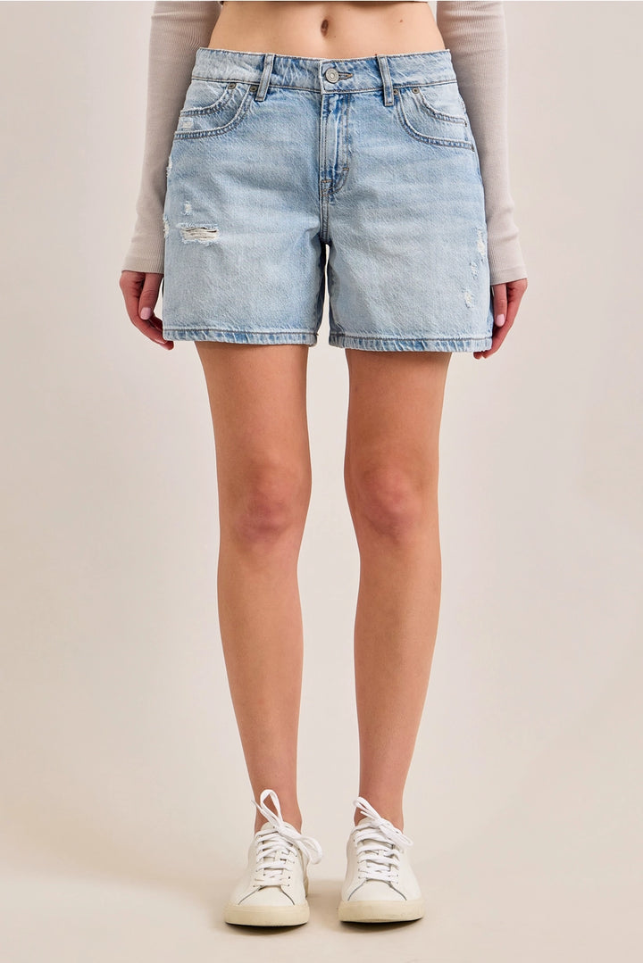 Woman wearing denim shorts and tennis shoes on plain background
