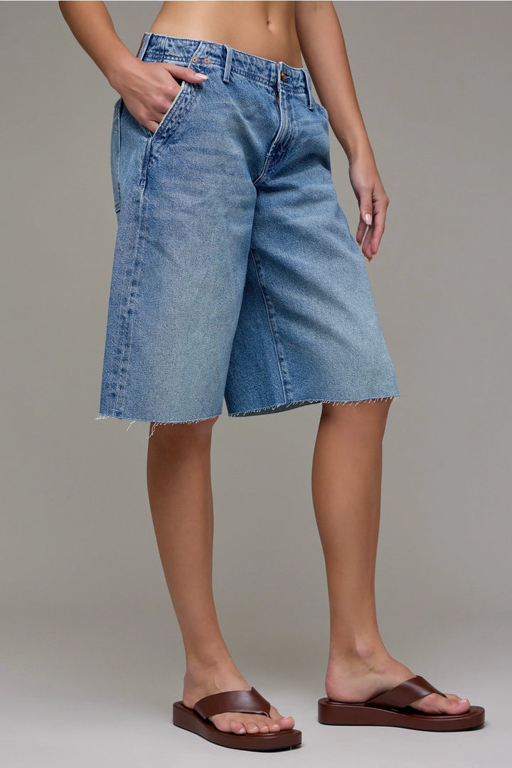 Person wearing blue denim shorts on a plain background