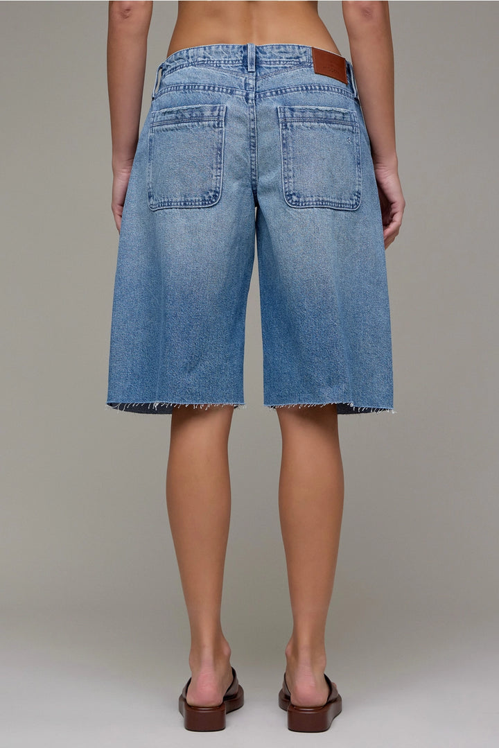 Person wearing blue denim shorts on a neutral background