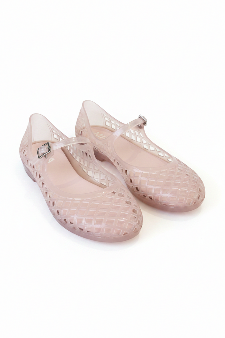 A pair of light pink jelly shoes with a grid-patterned cutout design and a small silver buckle on the strap, resting on white background
