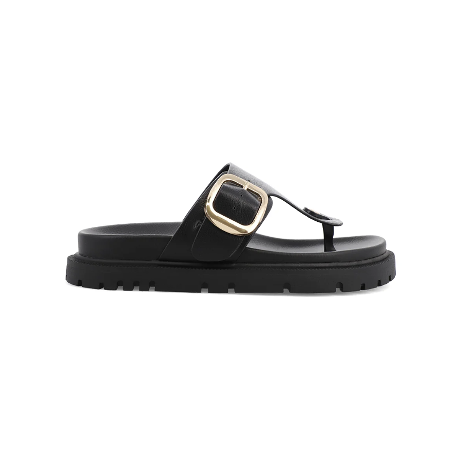 A black leather thong sandal with a chunky sole and a prominent gold-tone buckle detail on the strap, shown in a side profile view against a plain white background.
