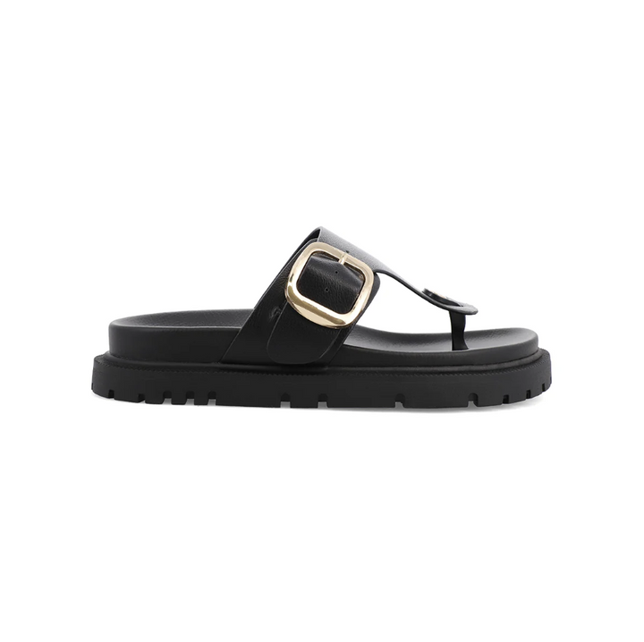 A black leather thong sandal with a chunky sole and a prominent gold-tone buckle detail on the strap, shown in a side profile view against a plain white background.