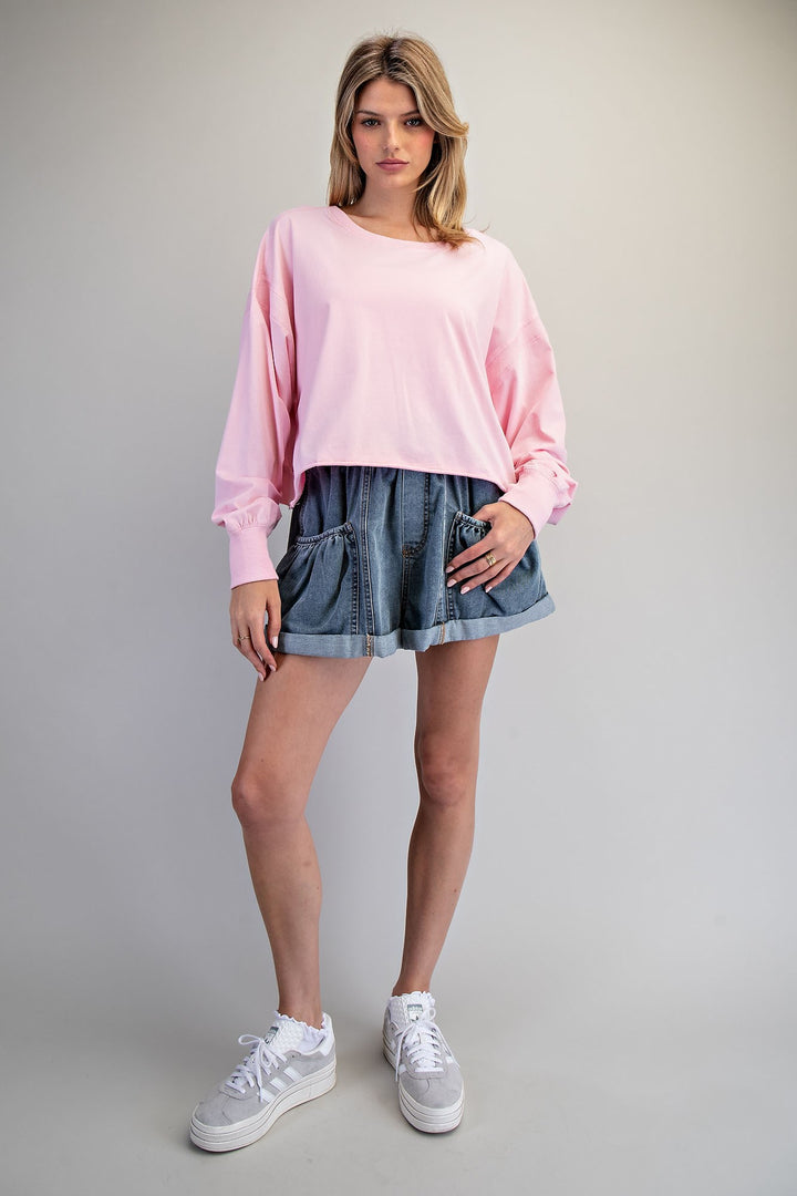 Woman wearing a pink sweater and denim skirt on a gray background