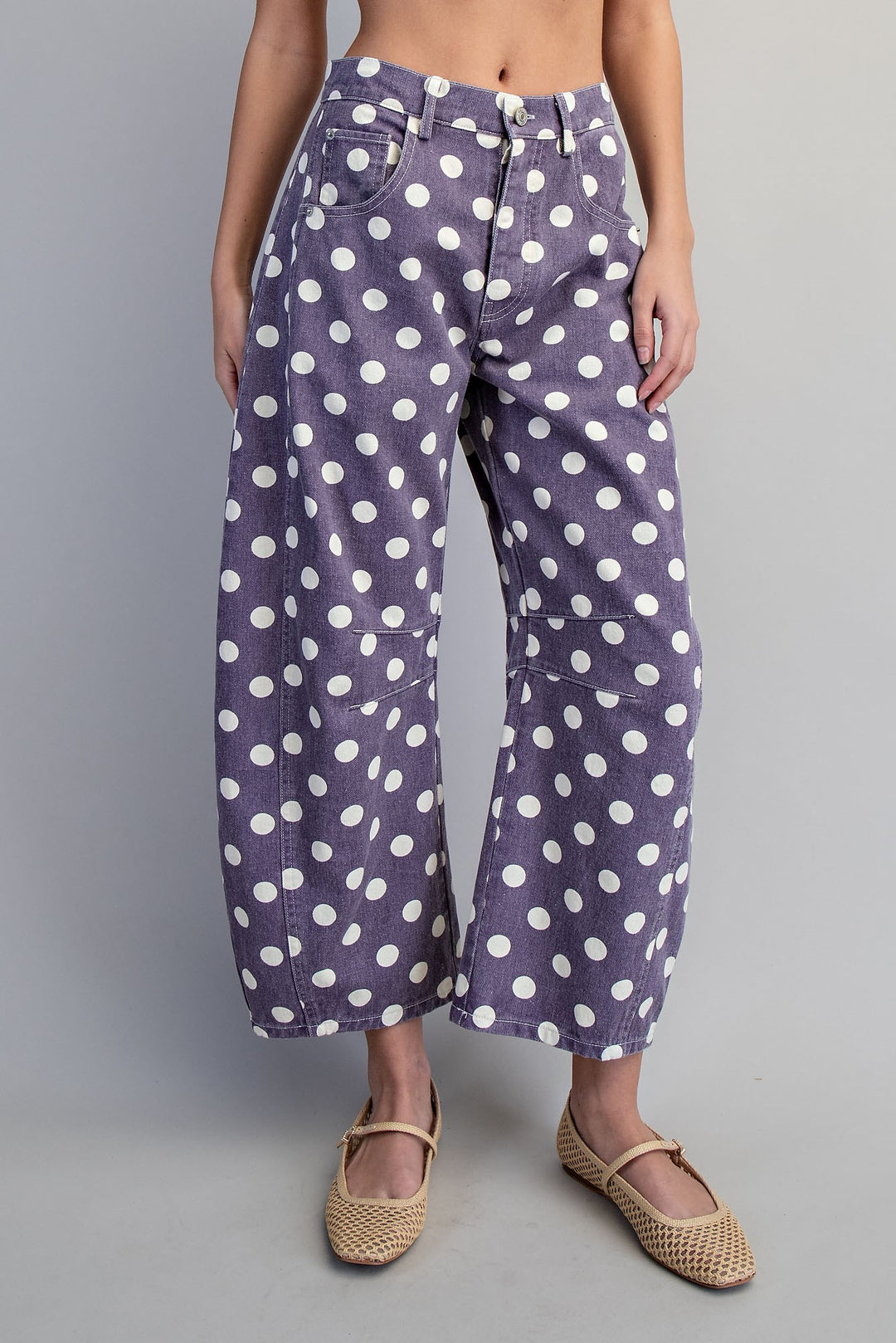 Woman wearing purple and white polka dot pants on plain background