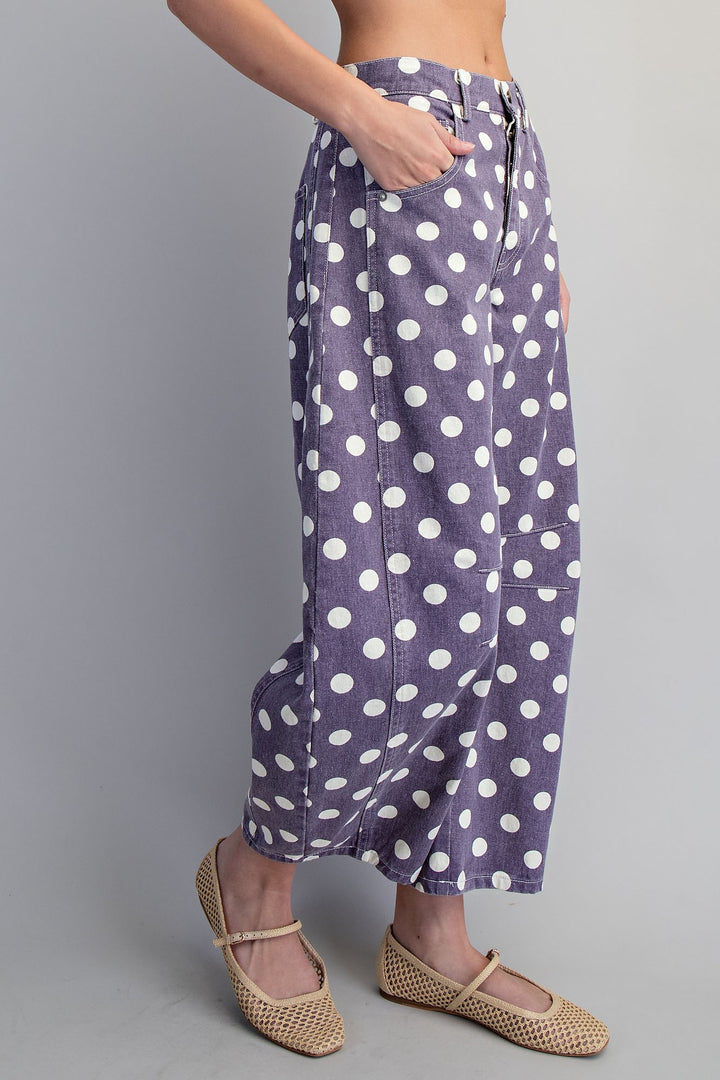 Woman wearing purple and white polka dot pants on plain background