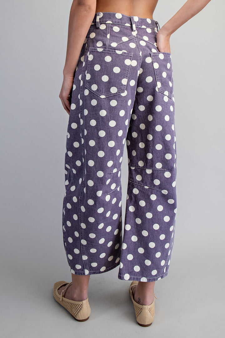 Woman wearing purple and white polka dot pants on plain background