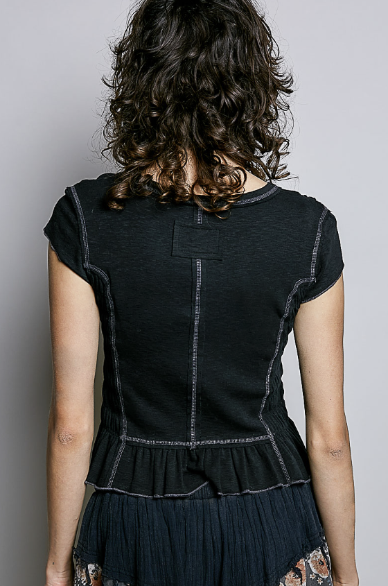 Woman wearing smocked black baby tee on plain background