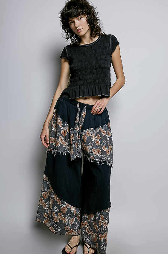 Woman wearing smocked black baby tee on plain background