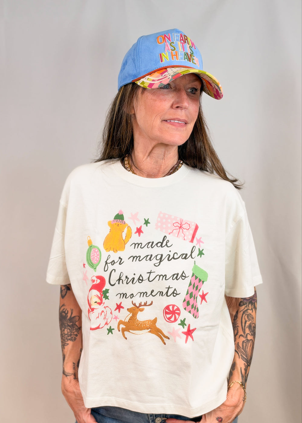 Woman wearing graphic tee with christmas items on it on plain background