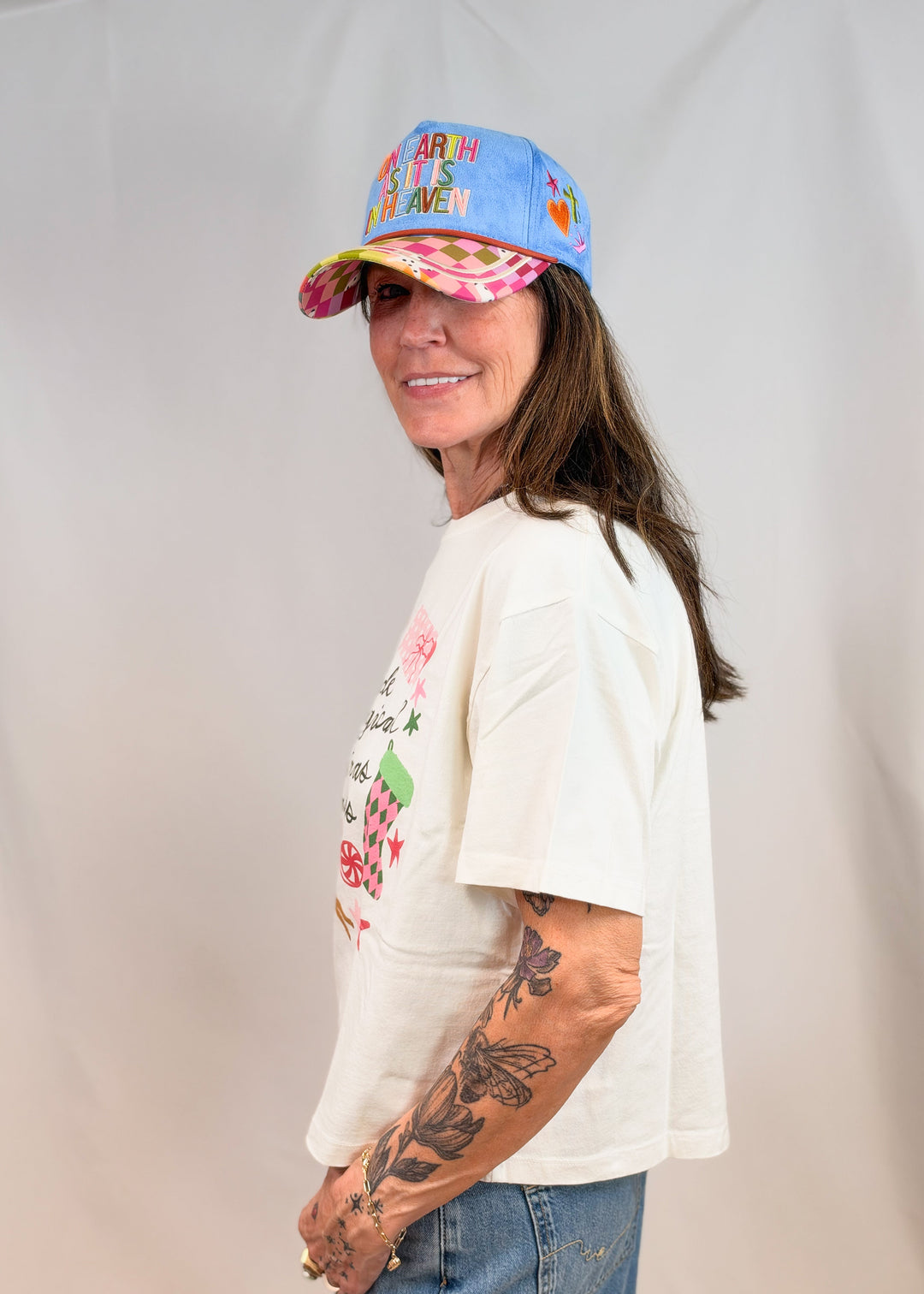 Woman shown from side wearing graphic tee with christmas items on it on plain background