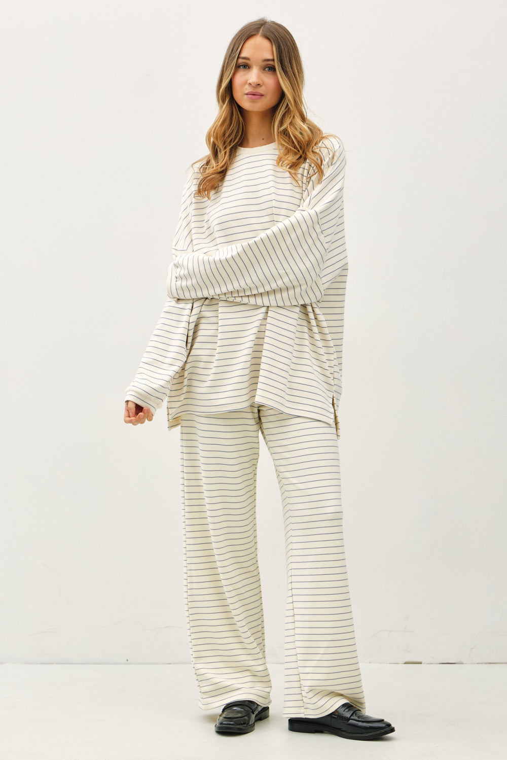 Woman wearing a matching striped sweater and pants set on a white background