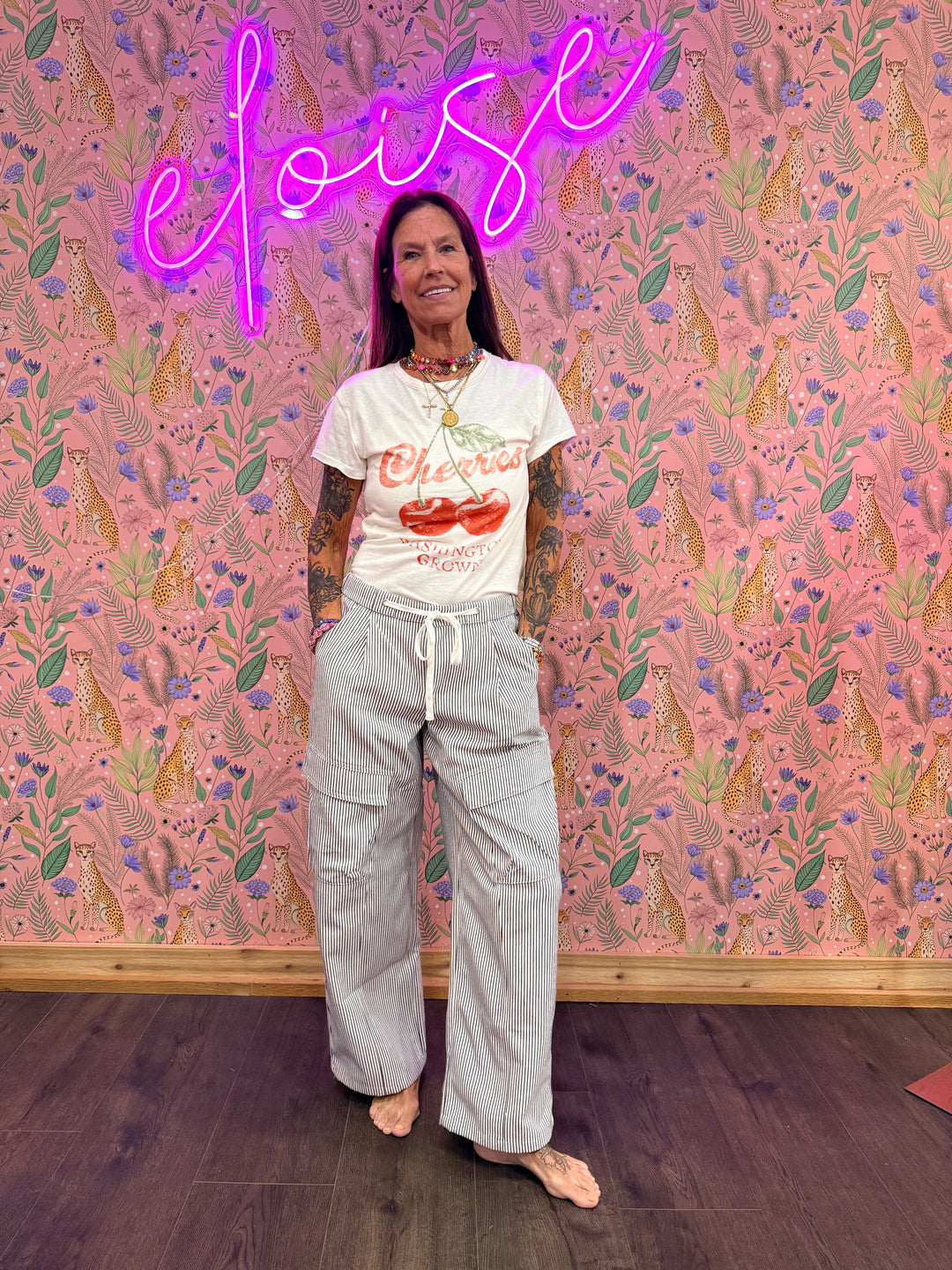 Woman wearing blue and white stripe pants with graphic tee on pink floral background