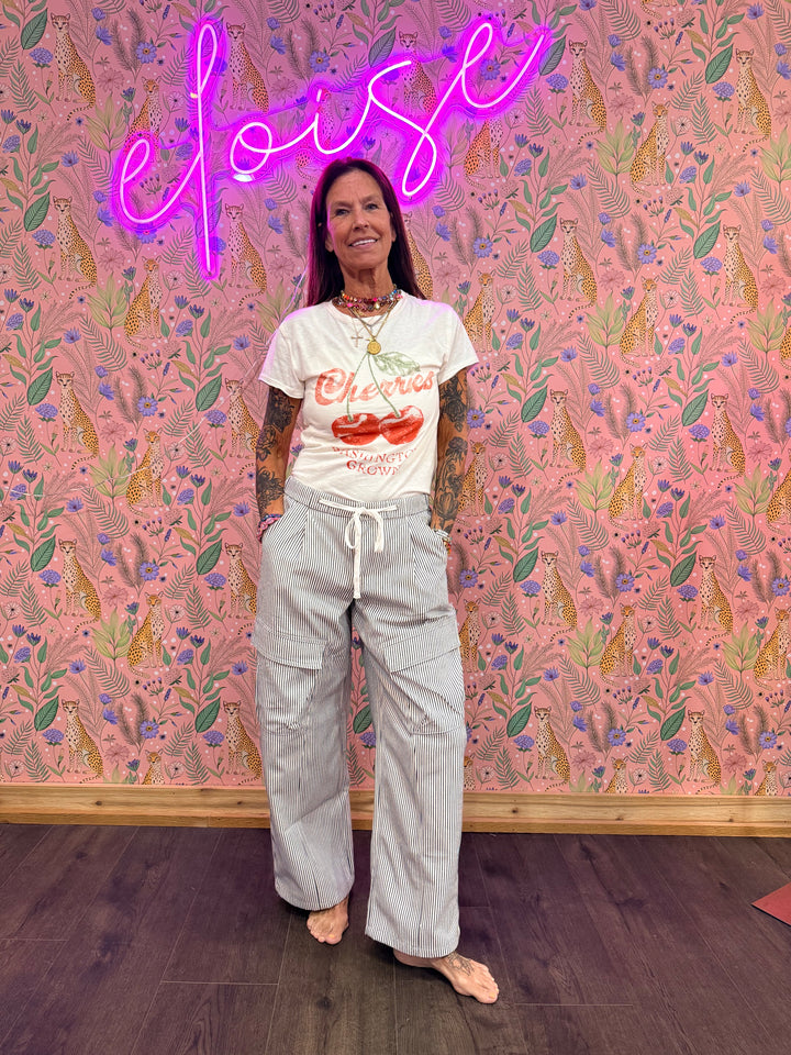 Woman wearing blue and white stripe pants with graphic tee on pink floral background