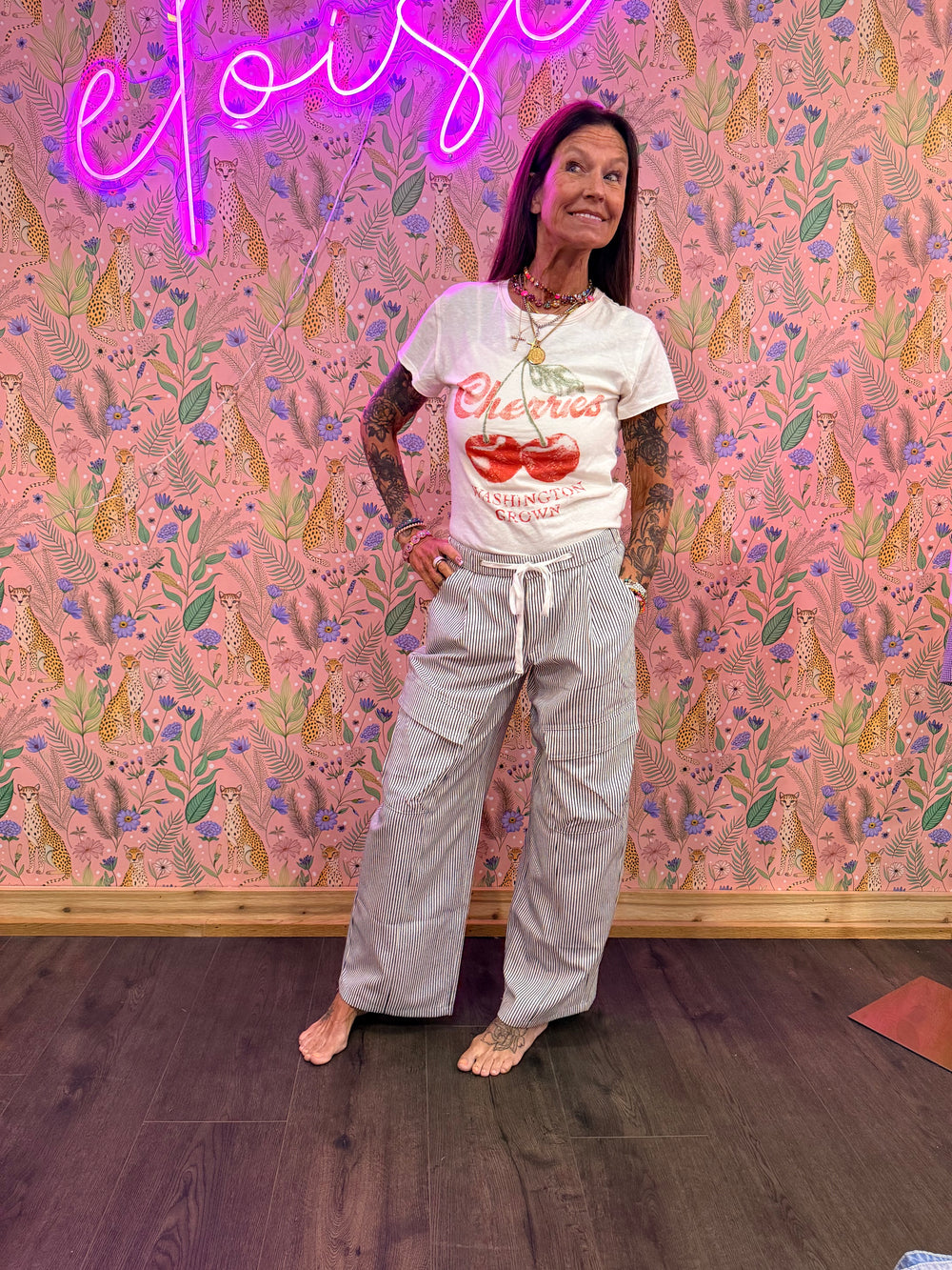 Woman wearing blue and white stripe pants and graphic tee on pink floral background
