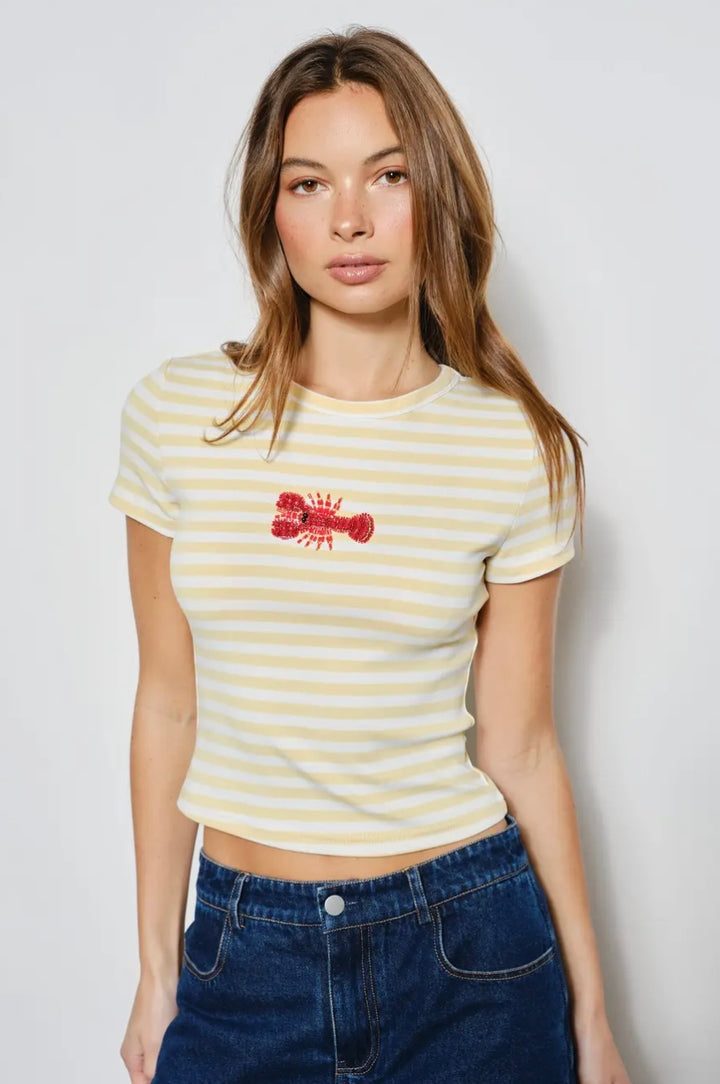 Woman wearing a yellow striped t-shirt with a red graphic on a plain background