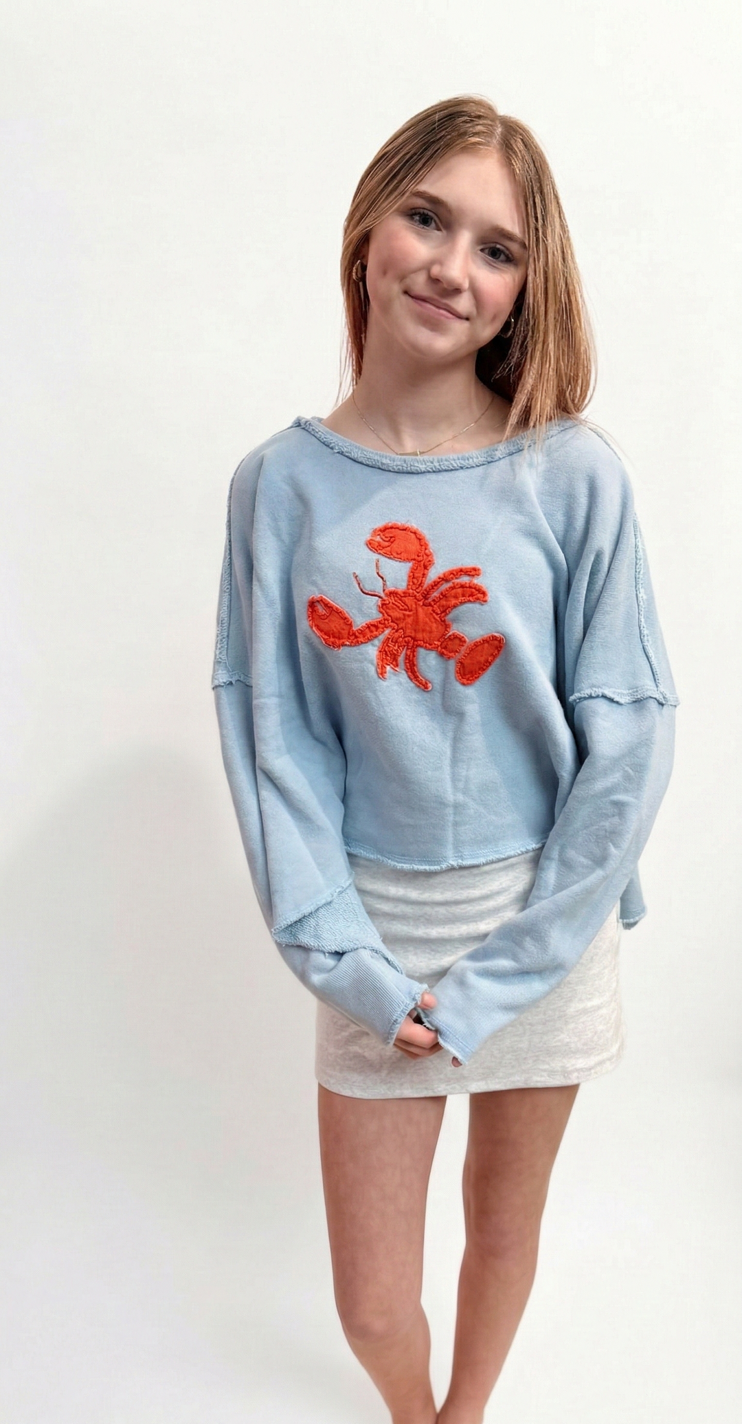 Person wearing a light blue sweatshirt with a red lobster design on a white background