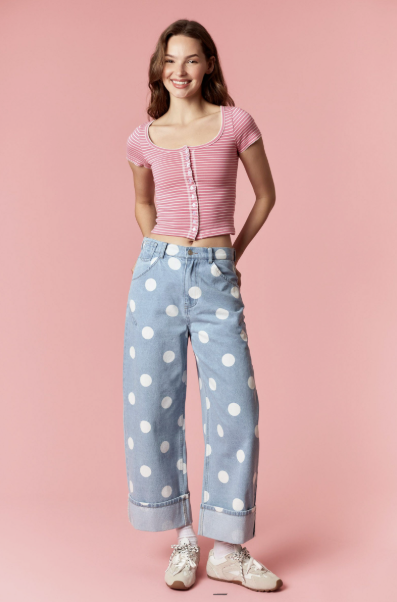 Woman wearing a pink striped shirt and polka dot jeans on a pink background