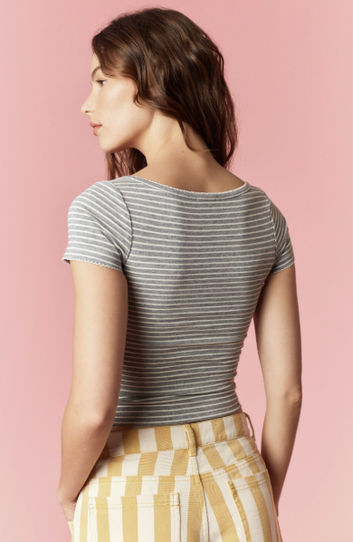 Woman wearing a striped shirt and checkered pants against a pink background