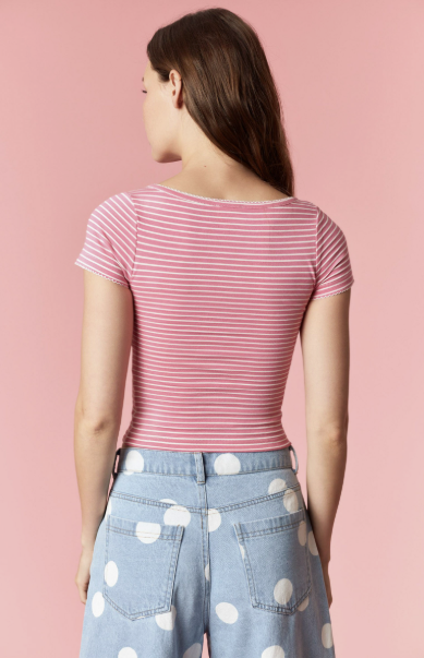 Woman wearing a pink and white striped shirt with polka dot pants on a pink background