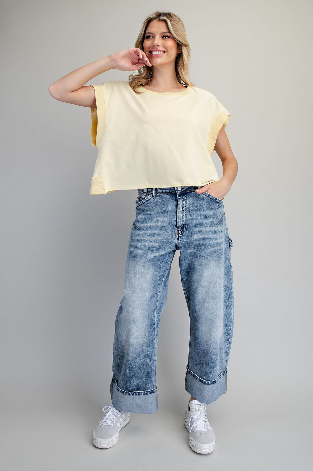 Woman wearing yellow tshirt and jeans on plain background