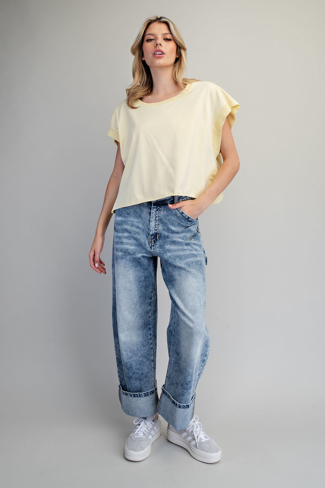 Woman wearing yellow tshirt and jeans on plain background