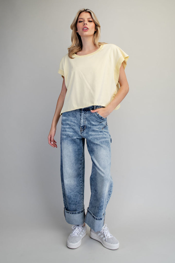 Woman wearing yellow tshirt and jeans on plain background