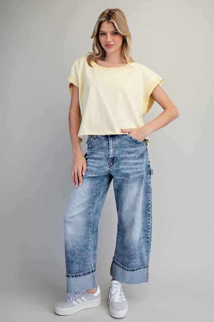 Woman wearing yellow tshirt and jeans on plain background