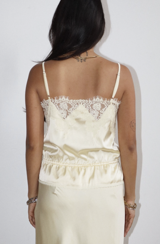 Woman wearing a cream-colored lace top against a white background