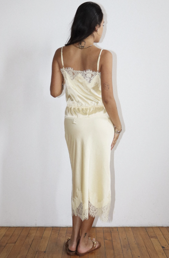 Woman wearing a cream-colored nightgown with lace details against a white background