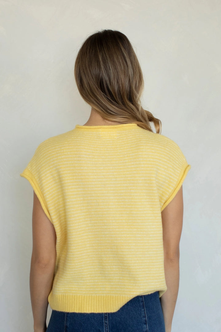 Woman wearing a yellow striped shirt against a plain background