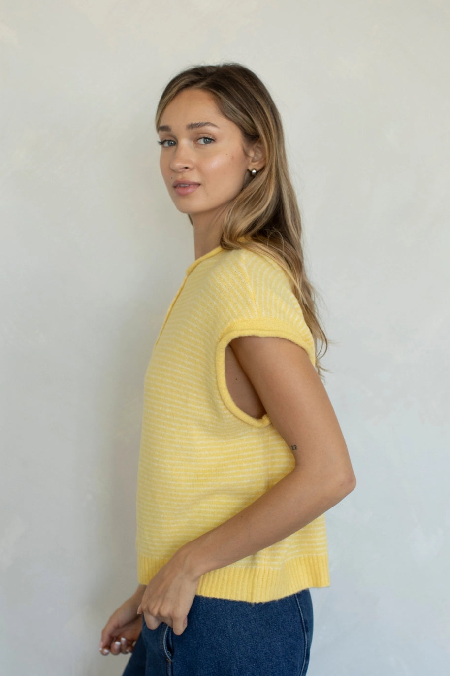 Woman wearing a yellow knit top against a plain background