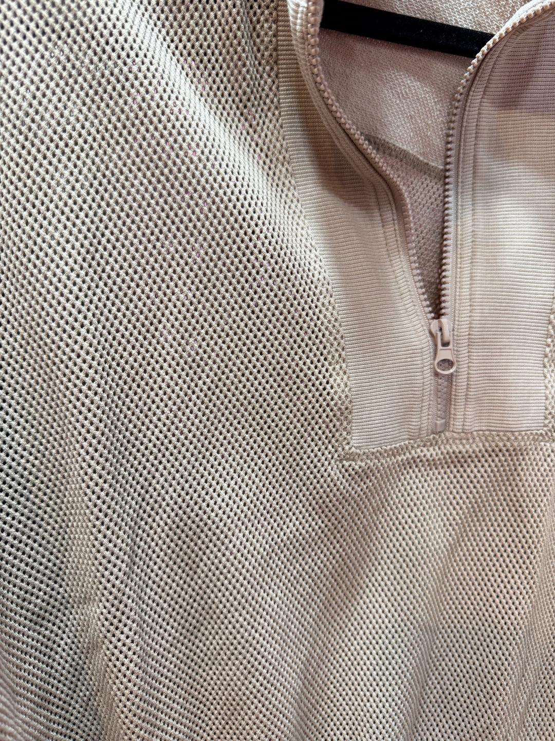Close-up of a beige mesh shirt with a quarter zip