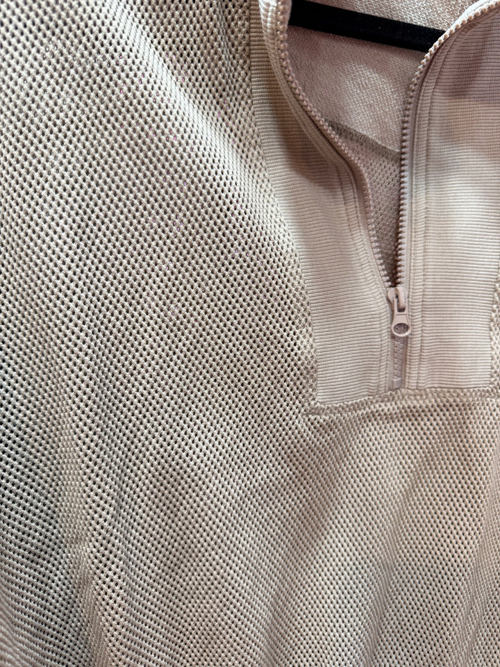 Close-up of a beige mesh shirt with a quarter zip