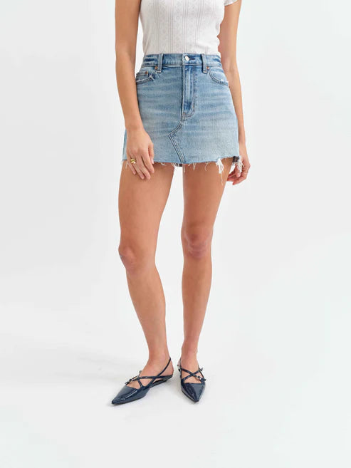 Person wearing a light blue denim skirt on a white background
