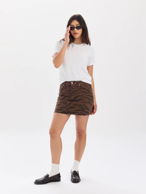 Woman wearing a white t-shirt, brown zebra-patterned skirt, and black loafers on a white background