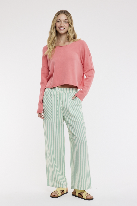 Woman wearing a pink top and striped pants on a white background
