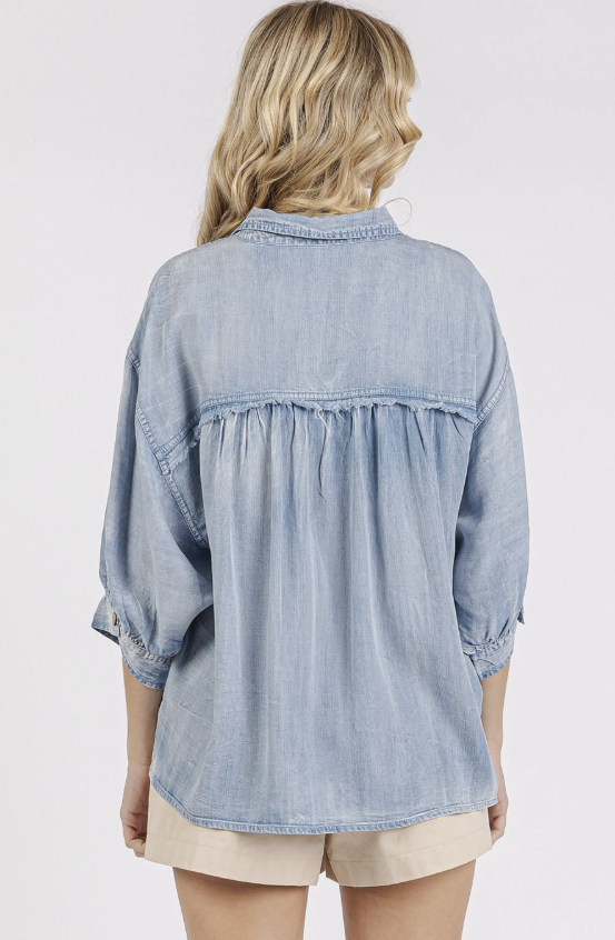 Light blue denim shirt worn by a person on a plain background