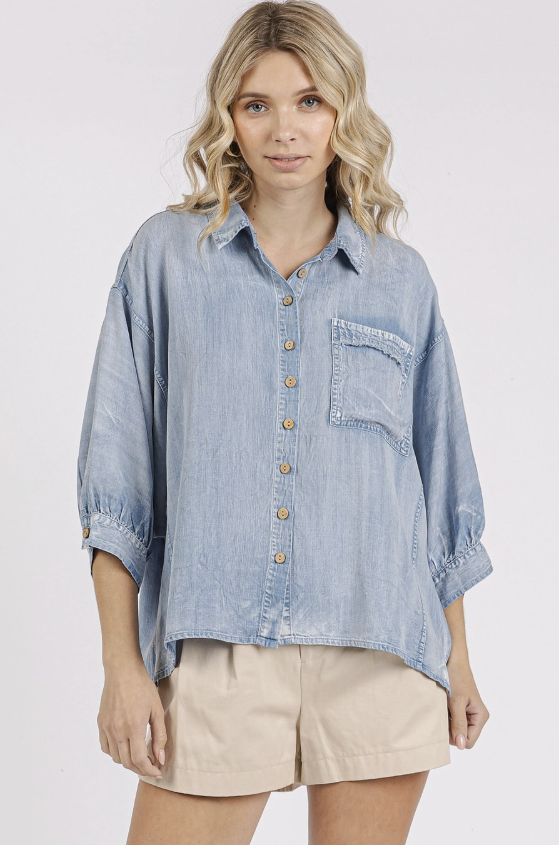 Woman wearing a light blue denim shirt and beige shorts on a white background