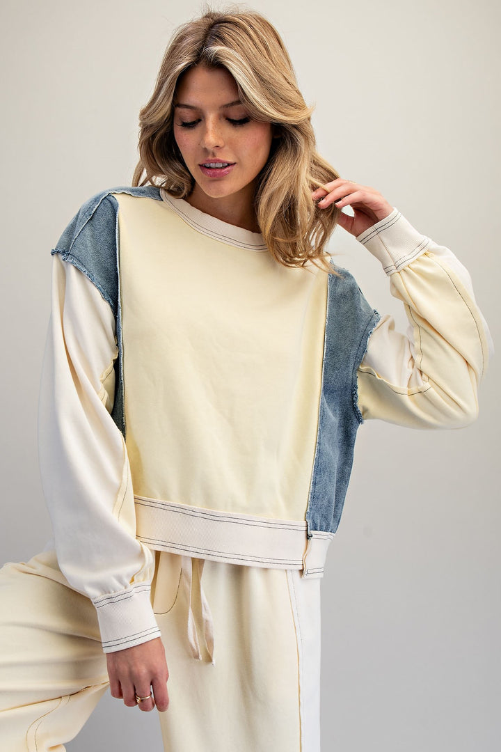 Woman wearing butter yellow and denim top and pants on plain background