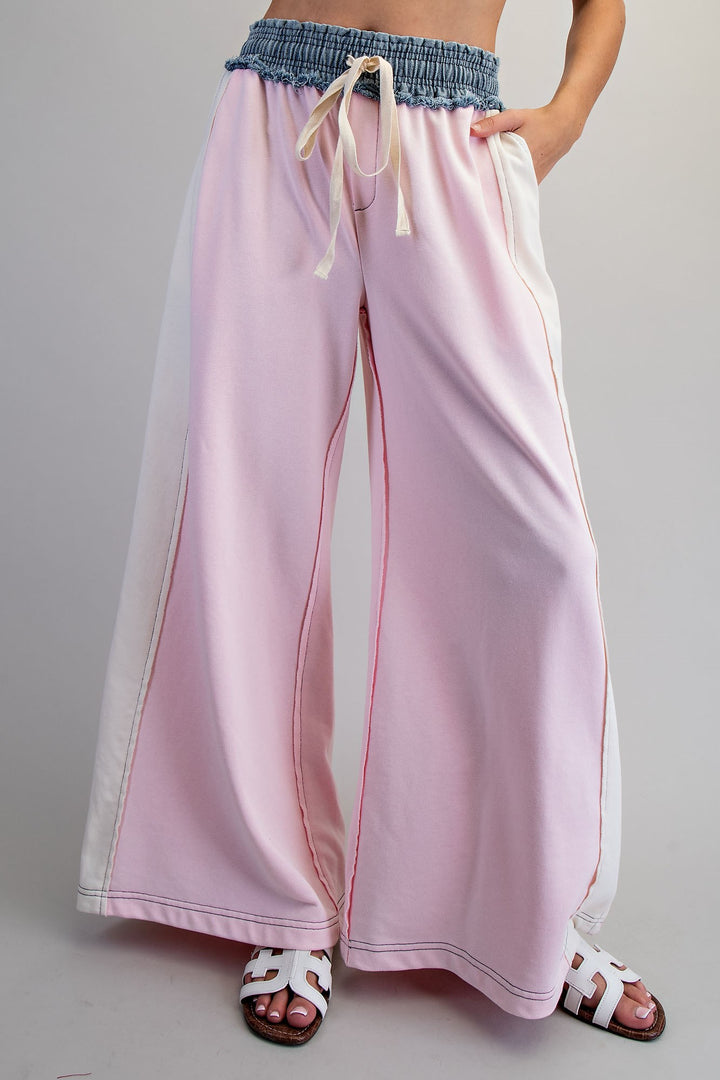 Woman wearing pink and denim pants on plain background