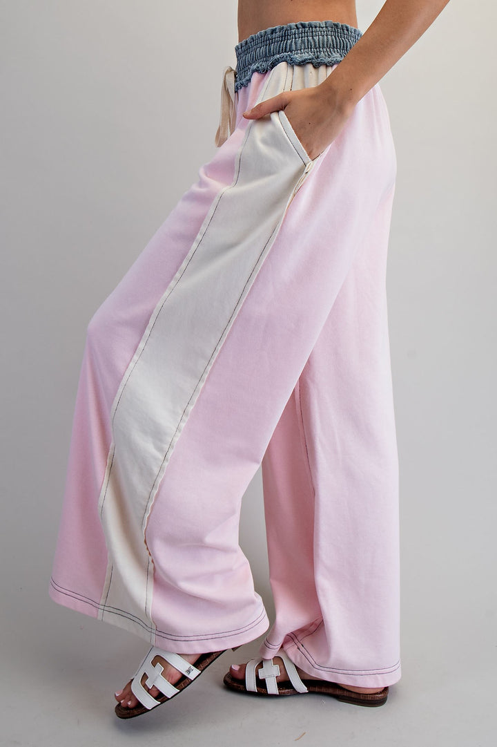 Woman wearing pink and denim pants on plain background