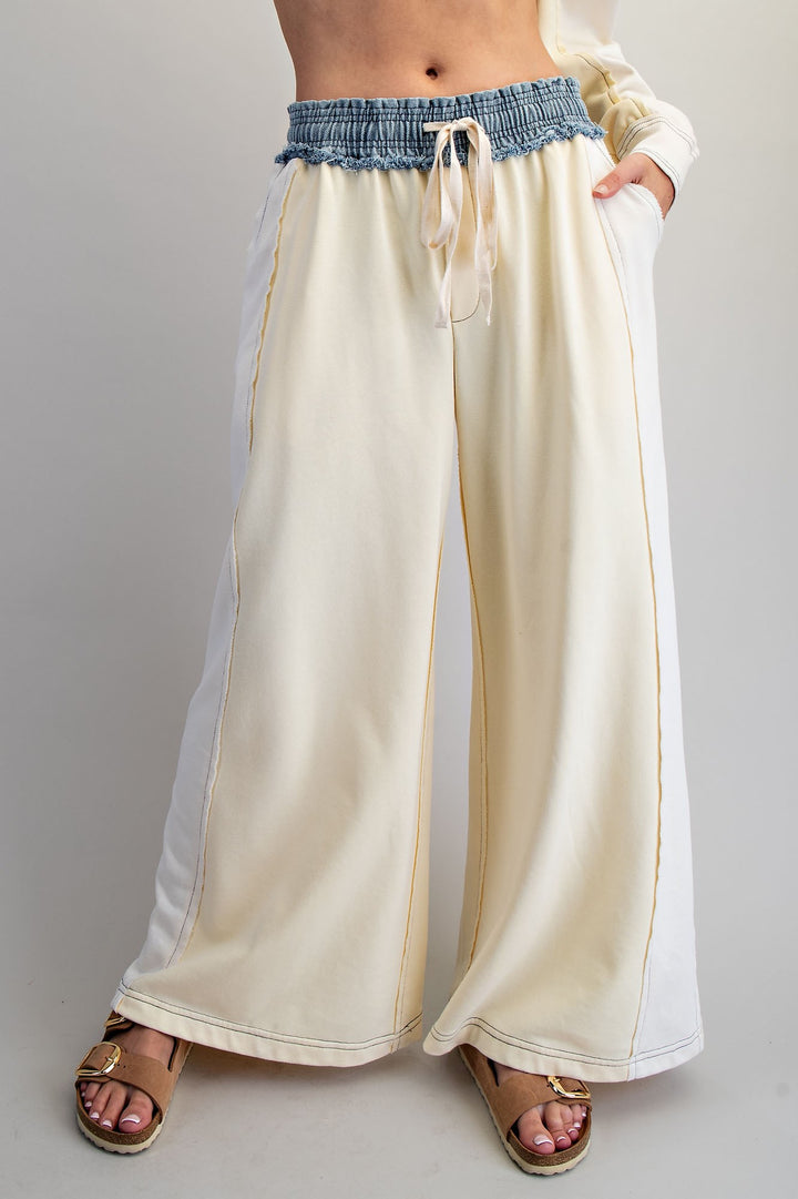 Beige wide-leg pants with blue denim waistband on a plain background
