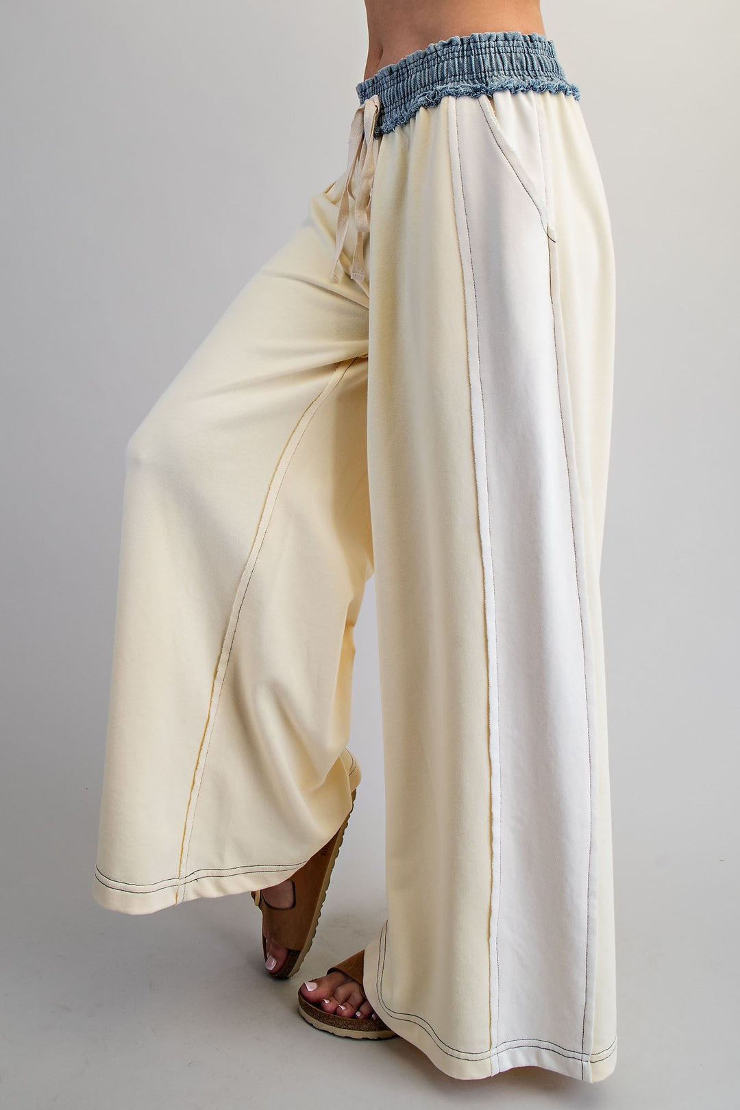 Beige wide-leg pants with blue waistband on a plain background