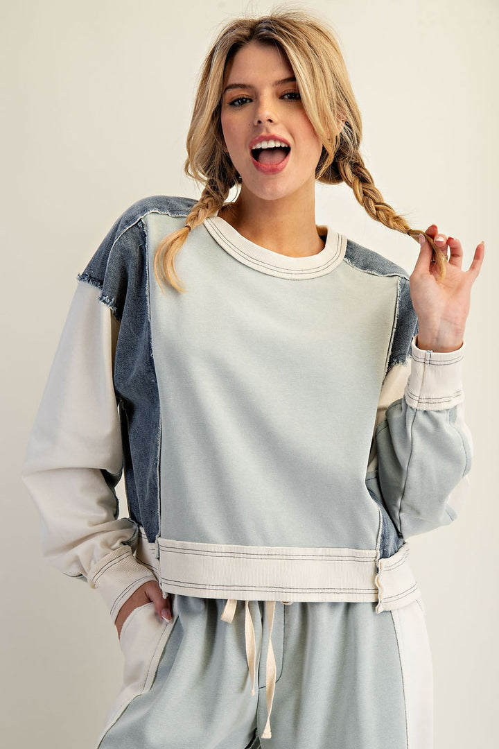 Woman wearing green and denim top on plain background