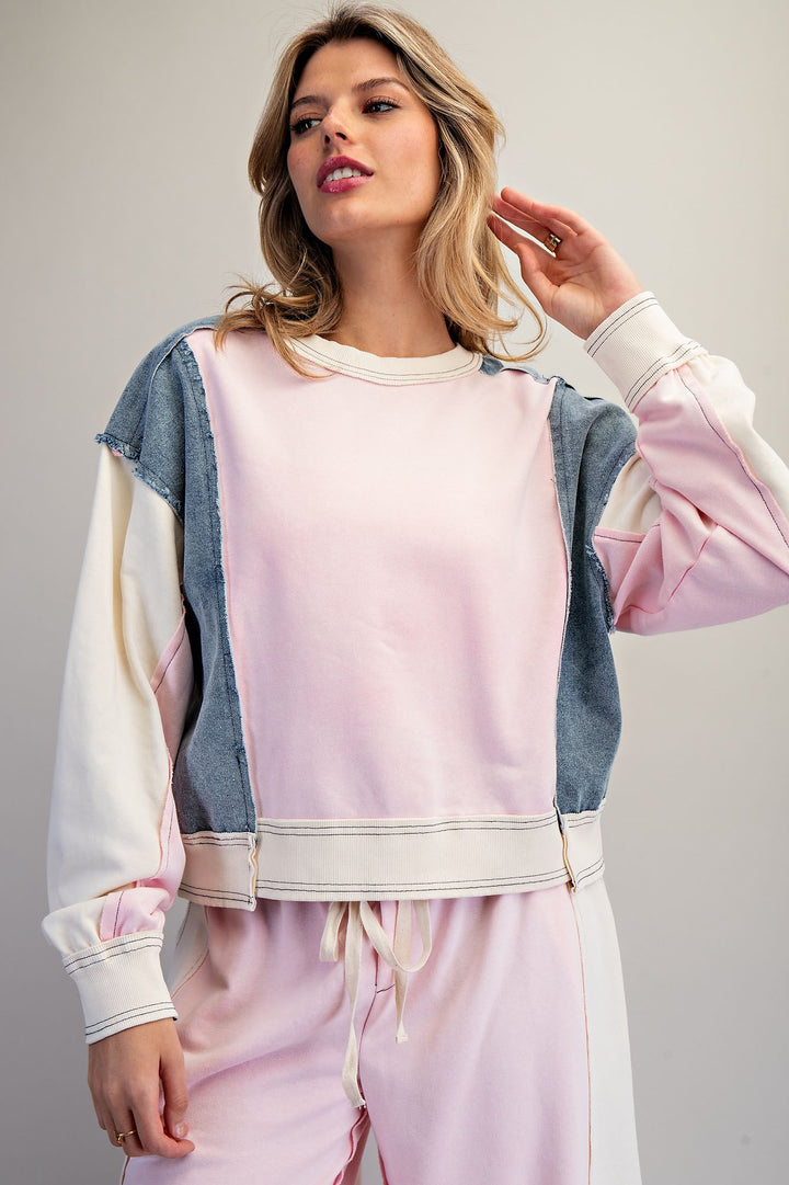 Woman wearing pink and denim top on plain background