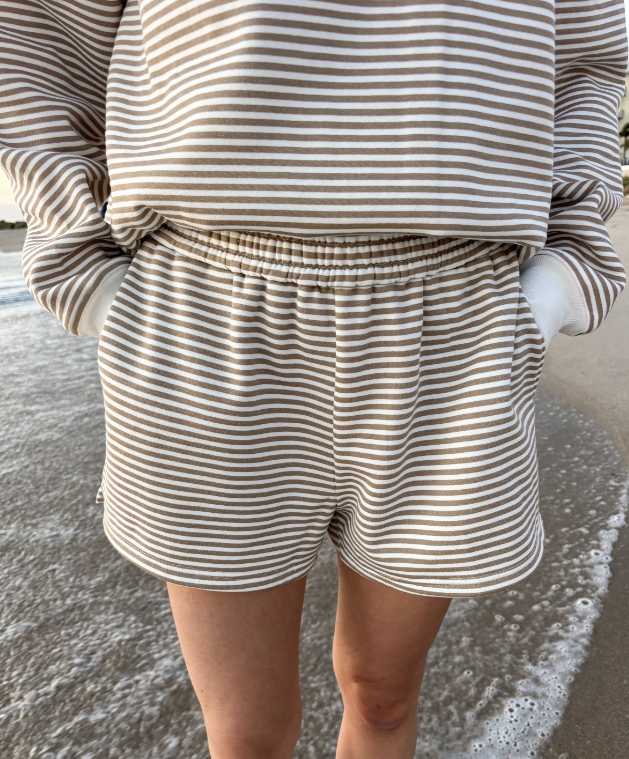 Woman wearing matching brown and white stripe set on the beach